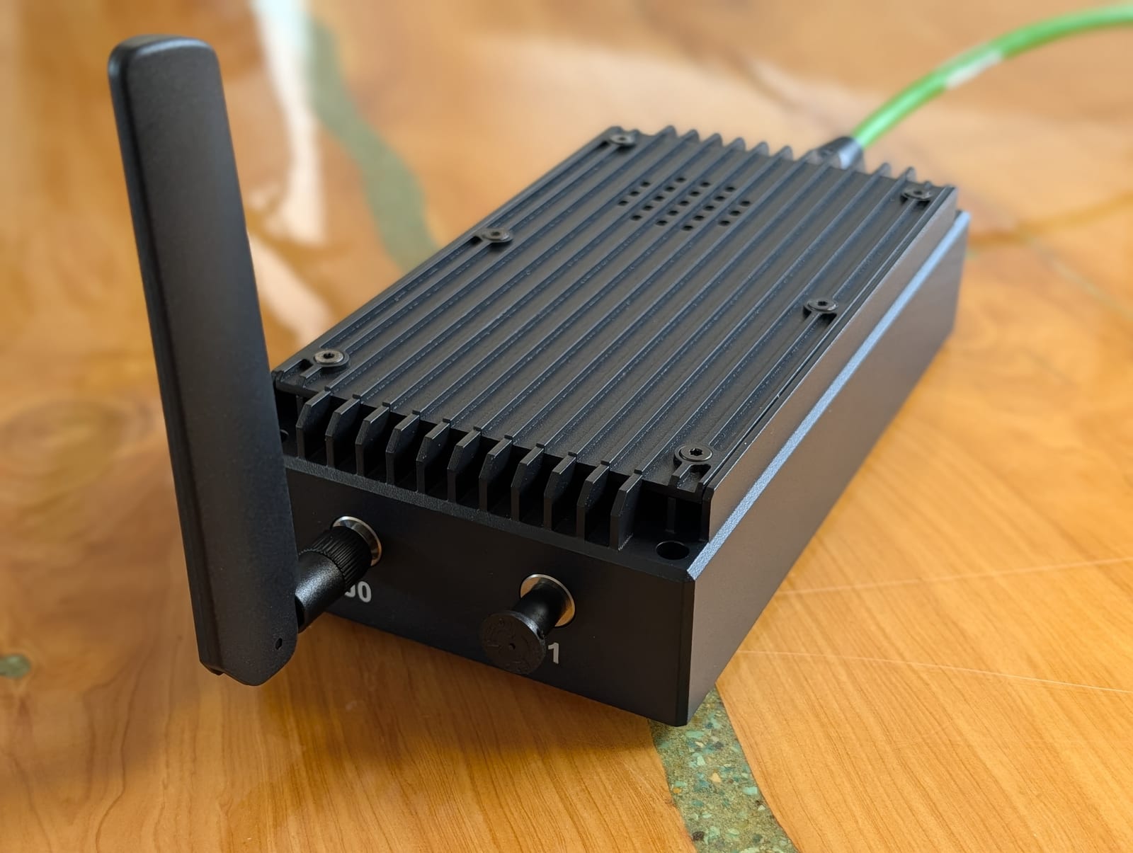 Top three-quarter view of the COYOTE unit showing the finned heat-sink lid, SMA RF connectors, and an articulating antenna on a workbench.