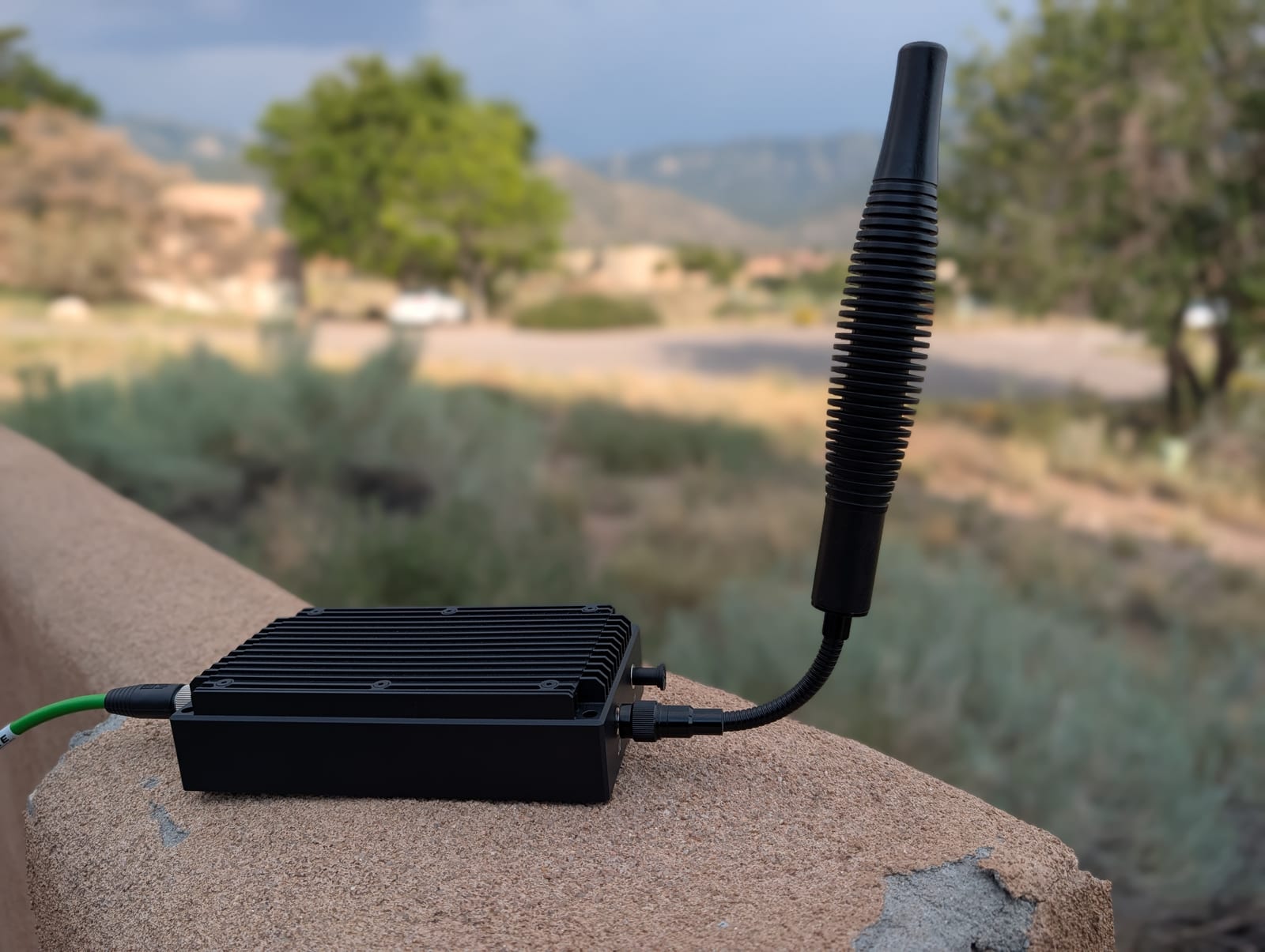 COYOTE deployed outdoors on a rock ledge with a rugged whip antenna and a single Ethernet/POE+ cable.